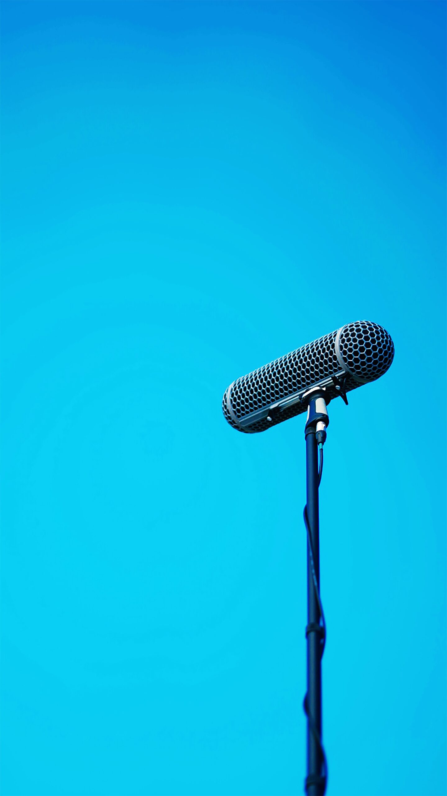 Een zwarte microfoon tegen een blauwe achtergrond.